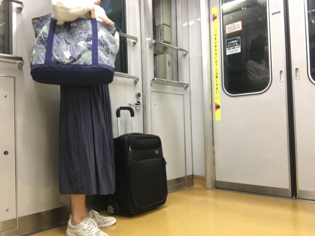 電車の中でキャリーケースを持つ女性